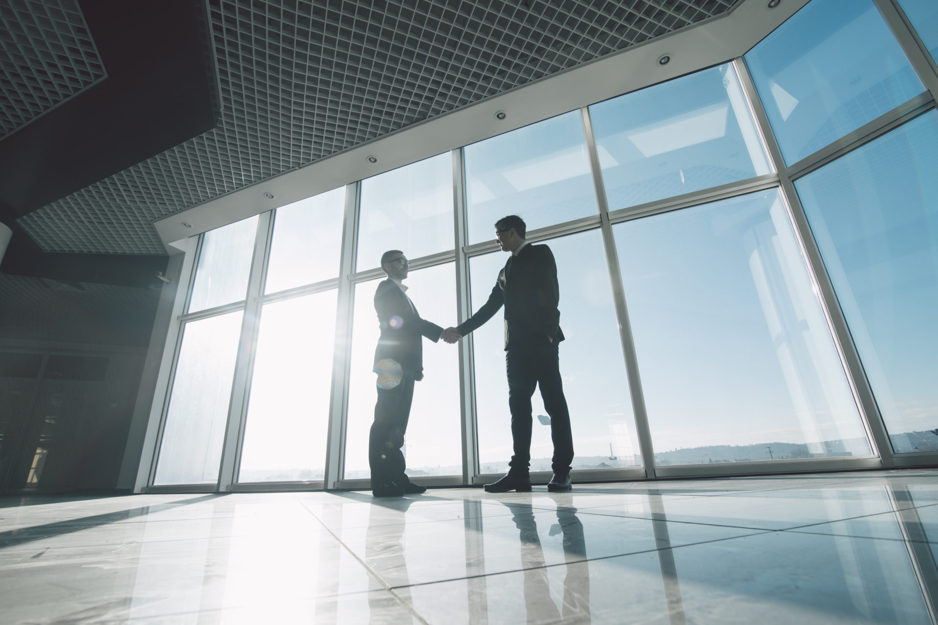 Two,Young,Businessmen,Are,Shaking,Hands,With,Each,Other,Standing